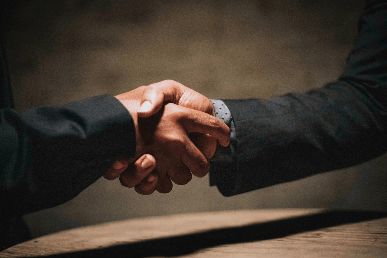 Two business people shaking hands over an office desk